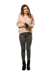A full-length shot of a Teenager girl with pink sweater holding a wallet over isolated white background