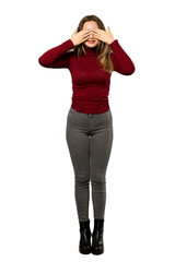 Fototapeta premium A full-length shot of a Teenager girl with turtleneck covering eyes by hands. Surprised to see what is ahead over isolated white background