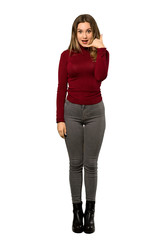 A full-length shot of a Teenager girl with turtleneck making phone gesture. Call me back sign over isolated white background