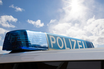 Polizeiauto mit Blaulicht vor blauem Himmel