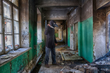Danger maniac with knife in hand, in leather mask of lague doctor and hood, inside old abandoned house
