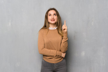 Teenager girl over textured wall pointing with the index finger a great idea