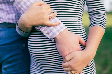 Future dad hugs his wife's pregnant tummy