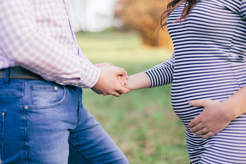 Future parents walk in the park. Husband holding his wife's hand