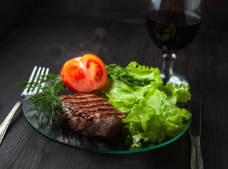 Hot steak on a dish with vegetables and glass of wine