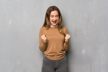 Teenager girl over textured wall shouting to the front with mouth wide open