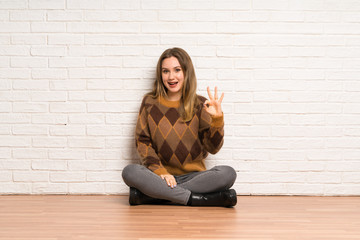 Fototapeta na wymiar Teenager girl sitting on the floor showing ok sign with fingers