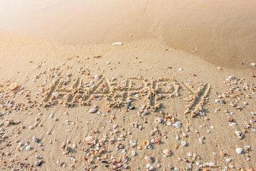 Fototapeta na wymiar Draw a happy message on the beach full of beautiful shells.