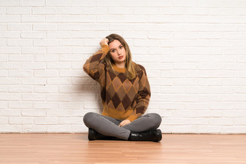 Fototapeta na wymiar Teenager girl sitting on the floor frustrated and takes hands on head