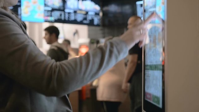 Woman Choosing Food Via Self-Service Machine at Fast Food Restaurant . People Using Self-Service Touch Terminal Makes a Purchase of Food