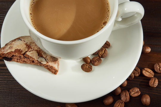 cropped image of a cup of coffee with milk, half a cookie, scattered coffee grains