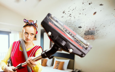 Angry housewife in apron with vacuum cleaner
