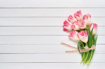Bouquet of pink tulips on white wooden background. Top view, copy space. Greeting card.