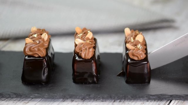 Mini mousse pastry dessert covered with chocolate glaze and peanuts. Modern european cake. French cuisine.