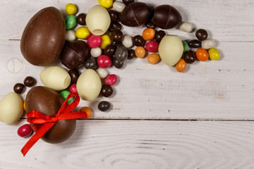 Naklejka na ściany i meble Easter composition with chocolate eggs on white wooden background