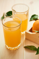 two glasses of fresh orange juice on a wooden background