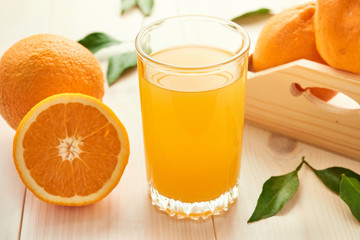 A glass of orange juice and oranges fruits on wooden background