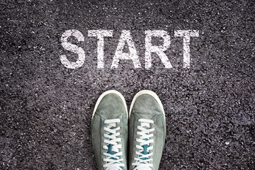 Sneaker shoes and the word START written  on asphalt ground, new life concept