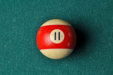Old billiard ball number 11 striped white and red on green billiard table, copy space