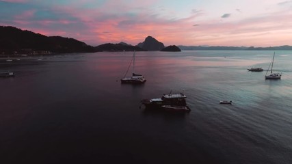 Aerial view of boats and yachts in the tropical bay on the sunset. El Nido, Palawan, Philippines. Marine tropical sunset over the sea. Travel concept.