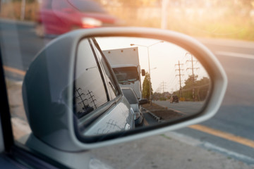 Cars run through the street from the White car's side view mirror.