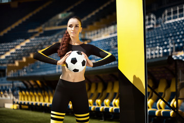 Athletic sporty woman in sportswear with soccer ball in the hands on stadium.