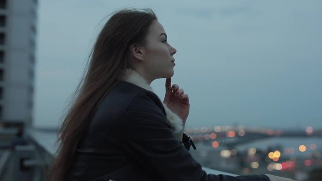Young woman relaxing and looks forward to evening city scape