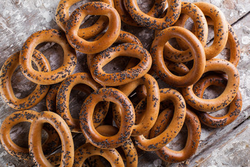 Photo of delicious bagels sprinkled with poppy seeds. Light wooden background