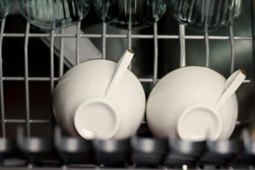 Dishwasher with glass cups and white porcelain cups washed dishes in a dishwasher 