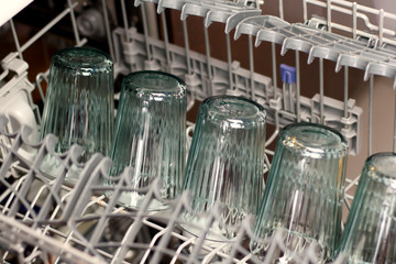Dishwasher with glass cups and white porcelain cups washed dishes in a dishwasher 