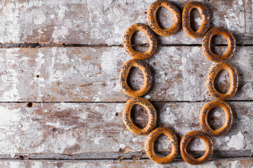 Photo of delicious bagels sprinkled with poppy seeds. Light wooden background