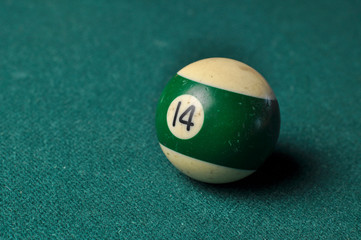 Old billiard ball number 14 striped white and green on green billiard table, copy space