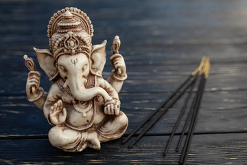 Hindu god Ganesh on black background. Statue on wooden table