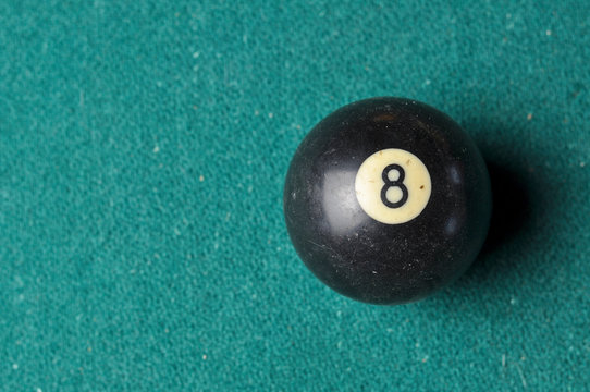 Old billiard ball number 8 black color on green billiard table, copy space