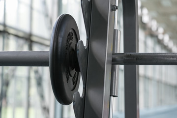 Close up view on a barbell with a pancake on the rack in the gym (shallow depth of field)