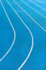 Fragment of blue synthetic surface of running tracks  of athletics stadium with white lines as texture, background