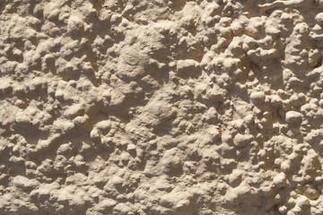 Texture of beige stone wall with rough stucco surface