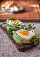 black bread with avocado, cucumber, cheese mass, prosciutto. Avocado bread and egg boiled and rosemary. Different items