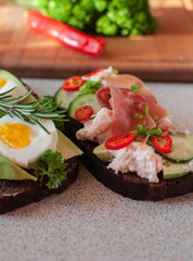 black bread with avocado, cucumber, cheese mass, prosciutto. Avocado bread and egg boiled and rosemary. Different items