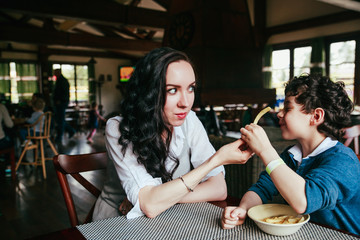 Mother and son eating fries in restaurant. Funny family dinner