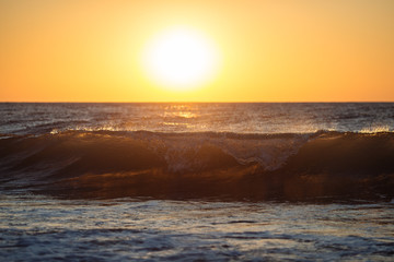 Fototapeta na wymiar waves over the sunrise