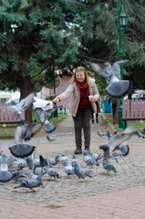 Blonde woman is feeding pigeons.