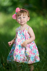 Portrait of a one-year-old girl with blue eyes and hair decoration in pink dress