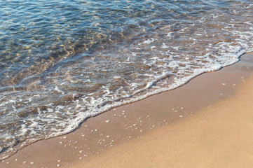 Sea wave on sandy beach.