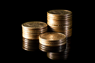 Stacks of golden coins on black reflective background.