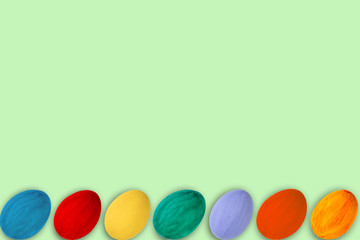 Happy Easter card. Colorful shiny easter eggs on green wooden table background. Copy space for text.