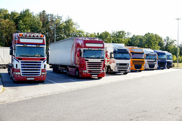 Several trucks lined up in a row on a parking lot. Travel break.