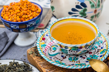 Buckthorn yellow berry fruit tea. Whole leaf hot tea drink in old styled colorful cup and saucer, teapot. Hot drink, water