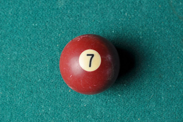 Old billiard ball number 7 brown color on green billiard table, copy space