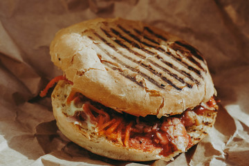 Grilled burger with vegetables and fried chicken. Crumpled brown paper. Fast food